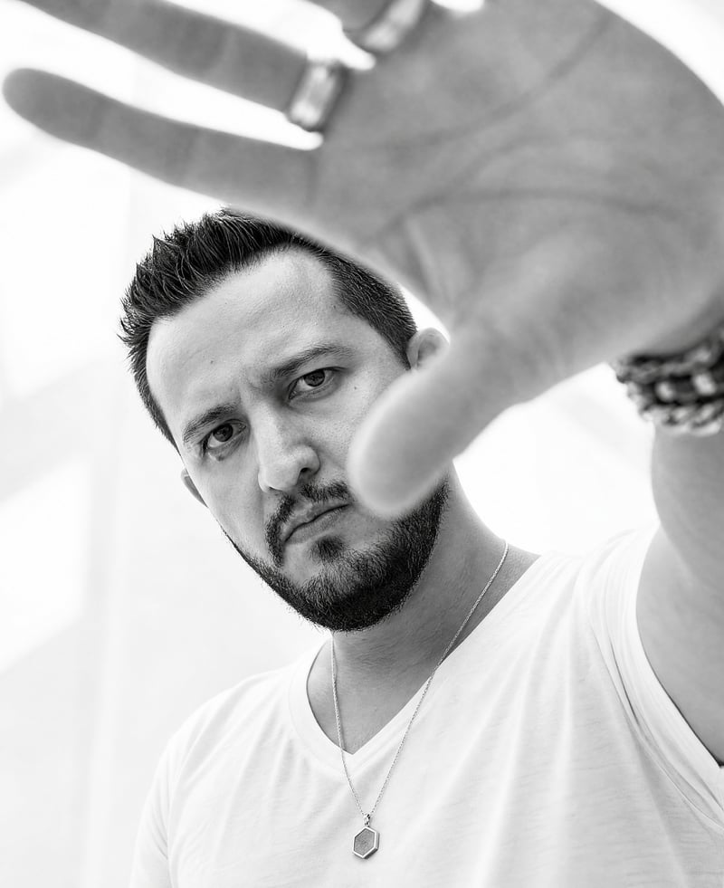 Retrato em preto e branco de André Alves com a mão estendida em direção à câmera